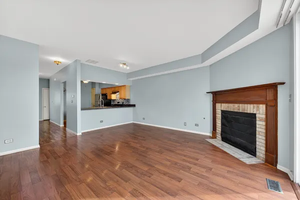 a view of an empty room with wooden floor fireplace and a window