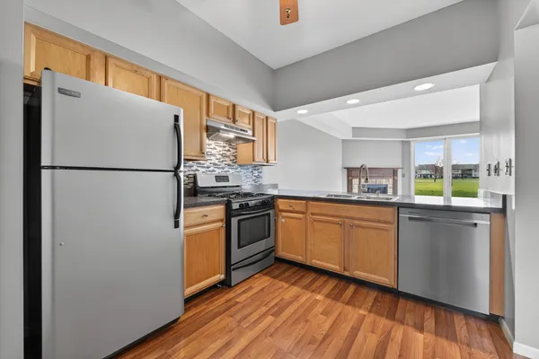 a kitchen with granite countertop appliances a sink cabinets and a wooden floor