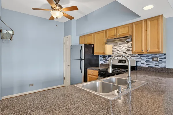 a kitchen with stainless steel appliances kitchen island granite countertop a refrigerator and a sink