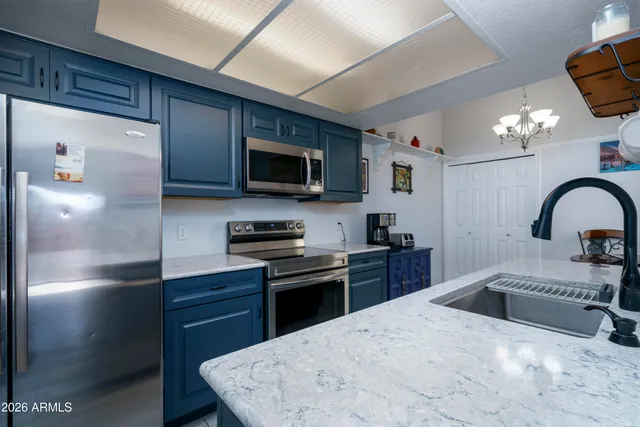 a kitchen with stainless steel appliances granite countertop a sink a stove top oven a chimney and a refrigerator with wooden floor