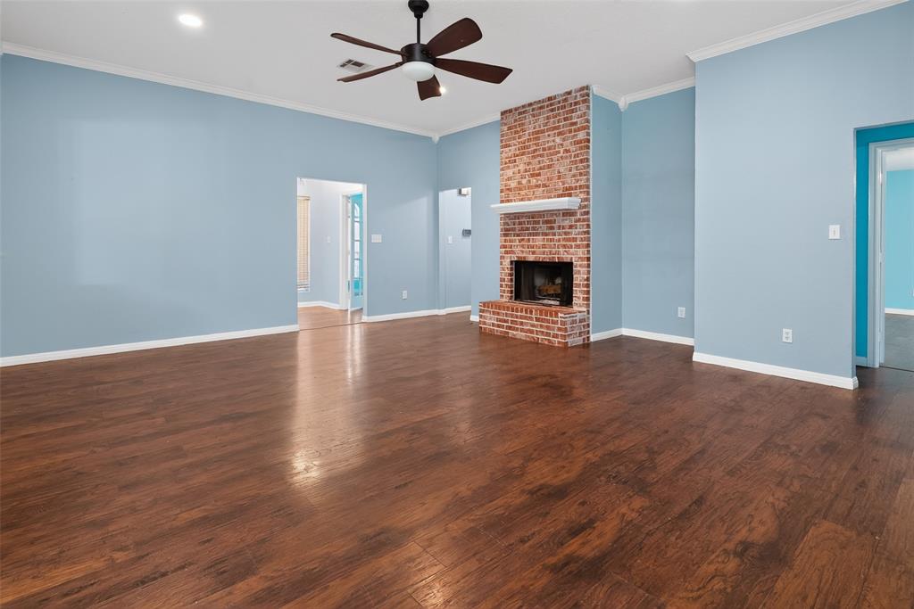 124 Topaz Circle Hewitt, TX 76643 - Photo 8 of 35 Spacious living area featuring wood-finish flooring, a brick fireplace with a white mantel, ceiling fan, crown molding, and recessed lighting