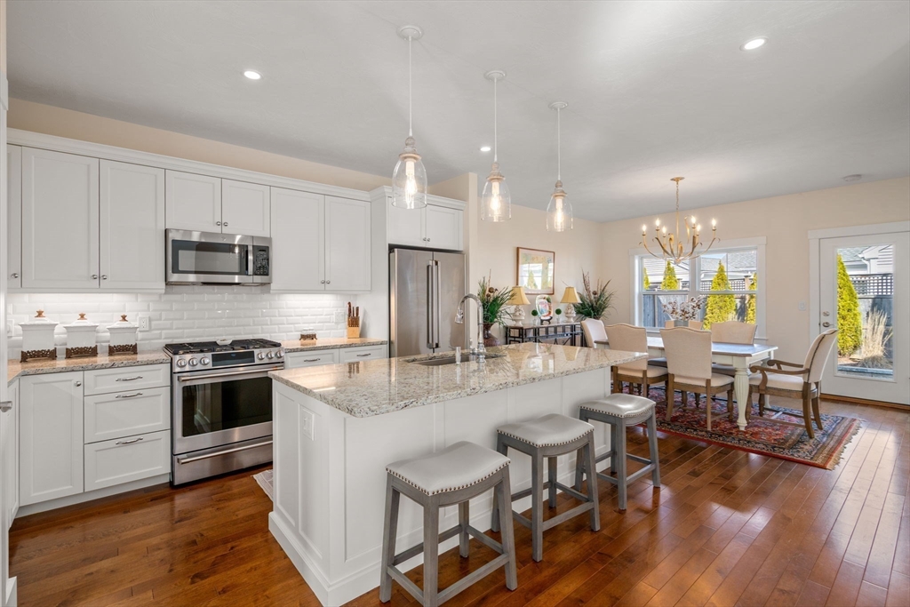 69 Abbey Road, Unit 69 Westwood, MA 02090 - Photo 3 of 16 a kitchen with stainless steel appliances granite countertop a stove top oven a sink dishwasher a dining table and chairs with wooden floor