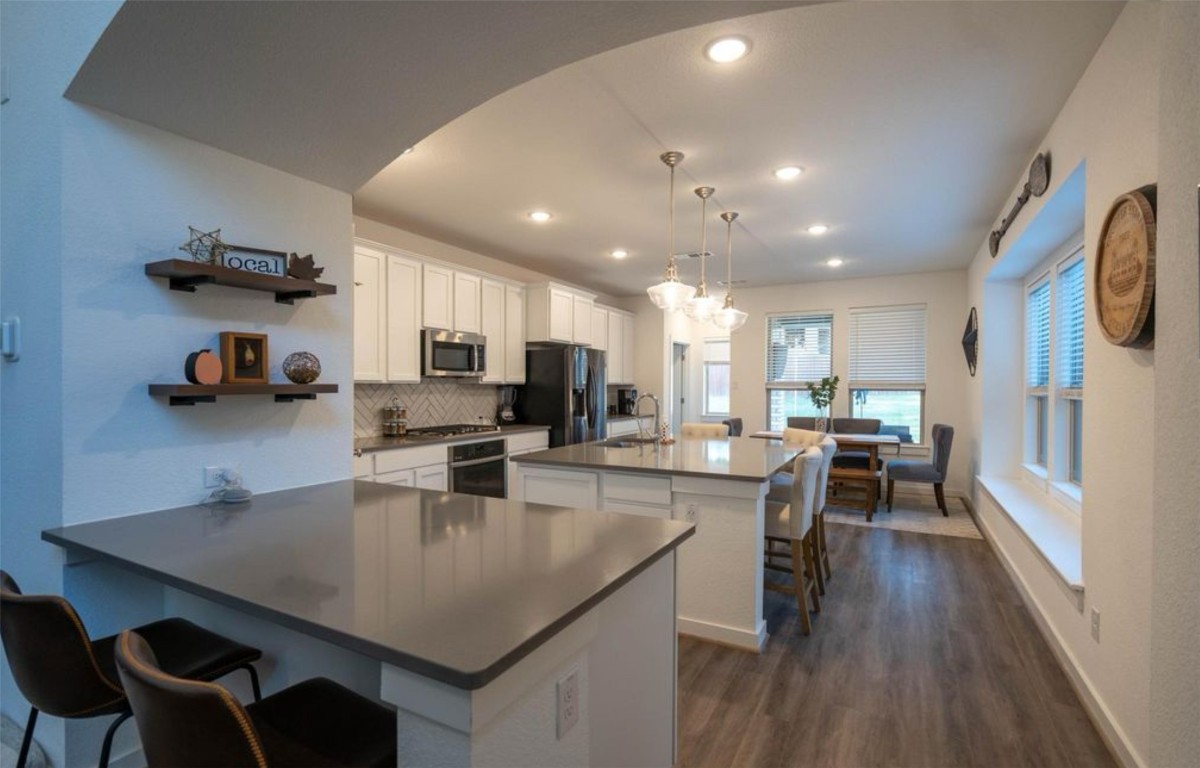 8205 Prairie Rye Drive Lago Vista, TX 78645 - Photo 1 of 1 a kitchen with kitchen island a dining table chairs and a refrigerator