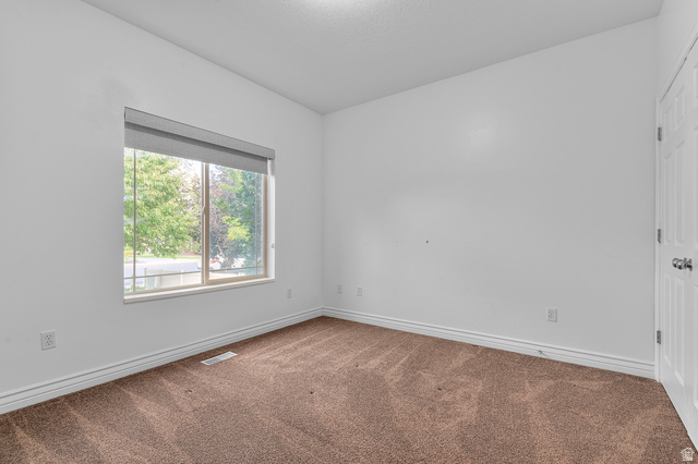 1501 West Elk Circle Mapleton, UT 84664 - Photo 27 of 39 Bright room featuring a large window with roller shades, neutral carpeting, white baseboards, and a paneled door