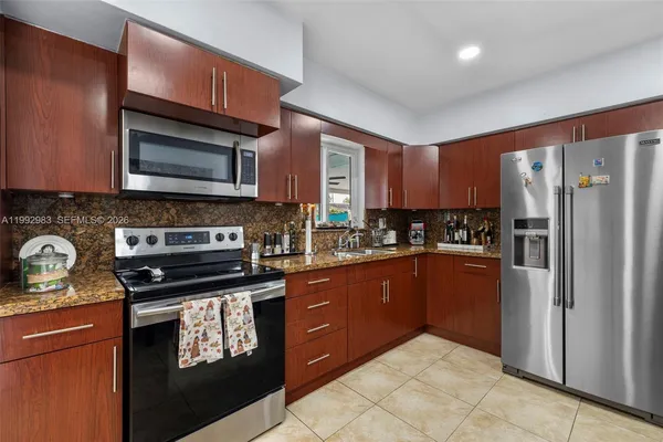 a kitchen with stainless steel appliances granite countertop a refrigerator a stove a sink a dining table and chairs