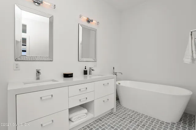 a bathroom with a white tub a sink and mirror