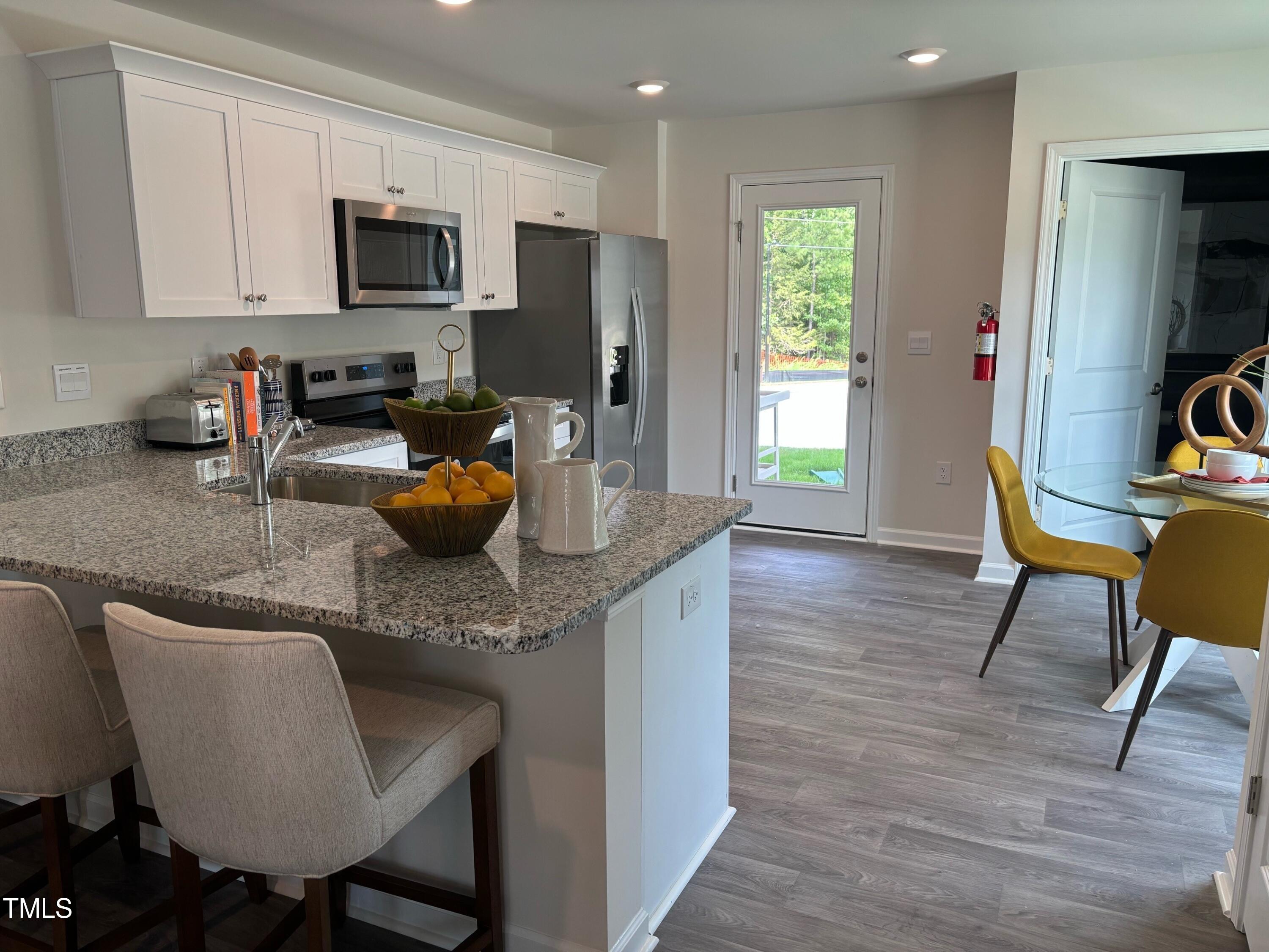 8750 Asher Gray Way Raleigh, NC 27616 - Photo 6 of 22 a kitchen with granite countertop a table chairs microwave and sink
