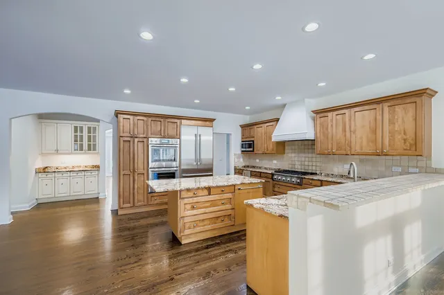 a kitchen with stainless steel appliances granite countertop a stove top oven a sink a counter space and cabinets