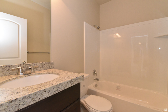 241 West Ridge Road Saratoga Springs, UT 84045 - Photo 17 of 21 Bathroom featuring a dark wood-finish vanity, light-toned granite countertop, undermount sink, brushed nickel faucet, and a white tub/shower combination with a single showerhead