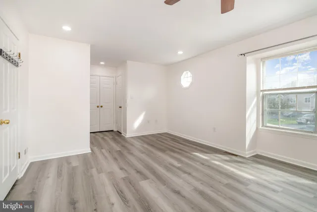 a view of an empty room with wooden floor and a window