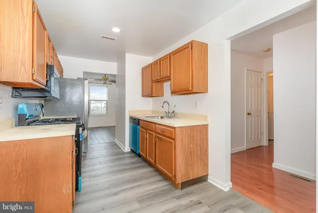 a kitchen with stainless steel appliances granite countertop a stove a sink dishwasher and a refrigerator with wooden floor