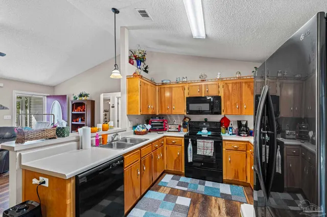 a open kitchen with stainless steel appliances granite countertop a stove refrigerator a dining table and chairs with wooden floor