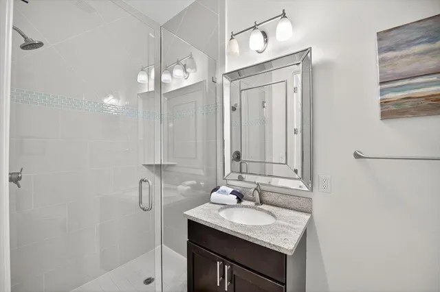 a bathroom with a granite countertop sink a mirror and shower