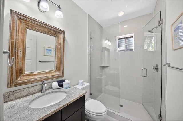 a bathroom with a granite countertop sink toilet a mirror and shower