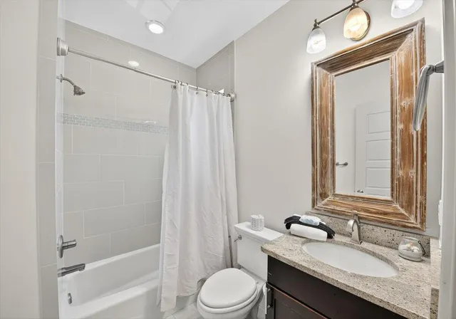 a bathroom with a granite countertop sink toilet a mirror and shower