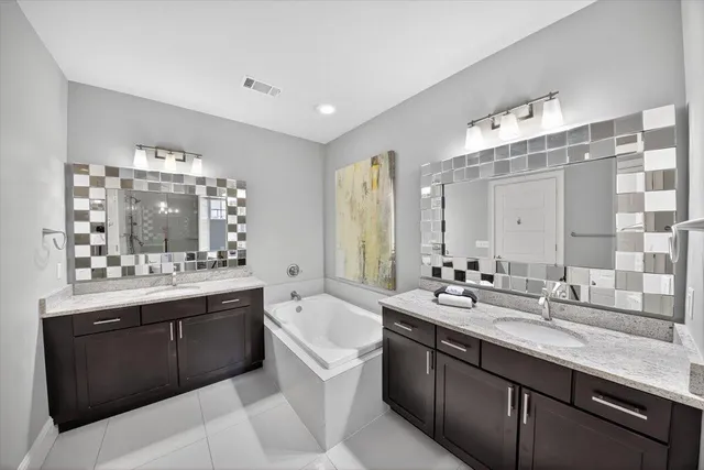 a bathroom with a tub sink double vanity and mirror