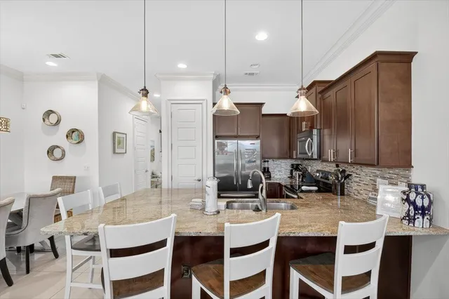 a kitchen with stainless steel appliances kitchen island granite countertop a dining table chairs sink and cabinets