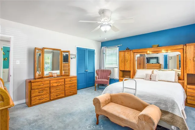 a living room with furniture a ceiling fan a lamp and a large window