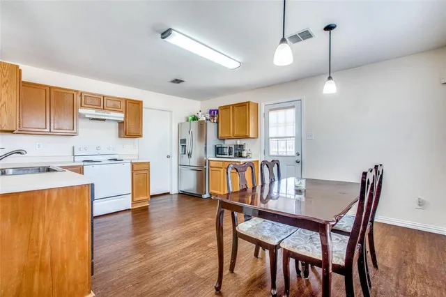 a kitchen with stainless steel appliances kitchen island granite countertop a table chairs and a refrigerator