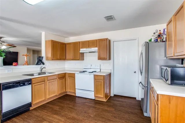 a kitchen with stainless steel appliances granite countertop a sink a stove a refrigerator cabinets and wooden floor