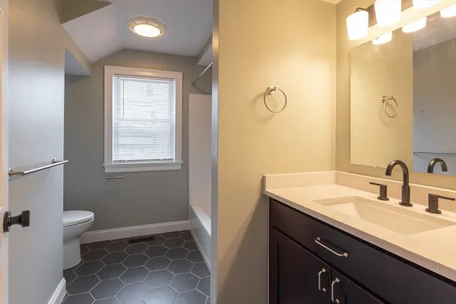 a bathroom with a sink a toilet a mirror and a window