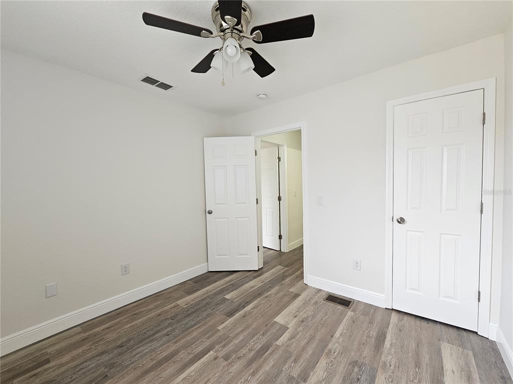 411 Australian Way Davenport, FL 33897 - Photo 21 of 24 an empty room with wooden floor ceiling fan and windows