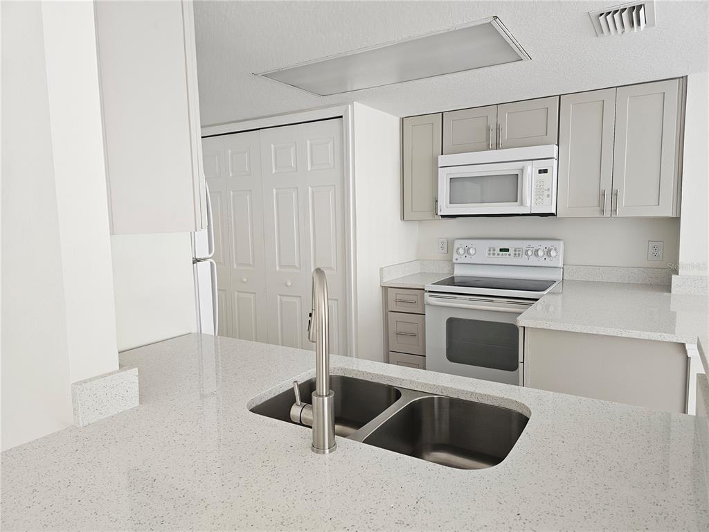 411 Australian Way Davenport, FL 33897 - Photo 3 of 24 a kitchen with white cabinets and stainless steel appliances