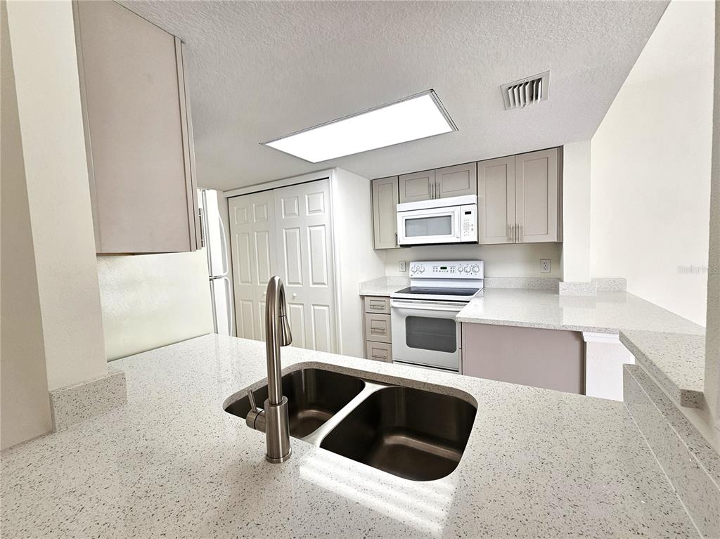 411 Australian Way Davenport, FL 33897 - Photo 5 of 24 a kitchen with granite countertop a stove a sink and a refrigerator