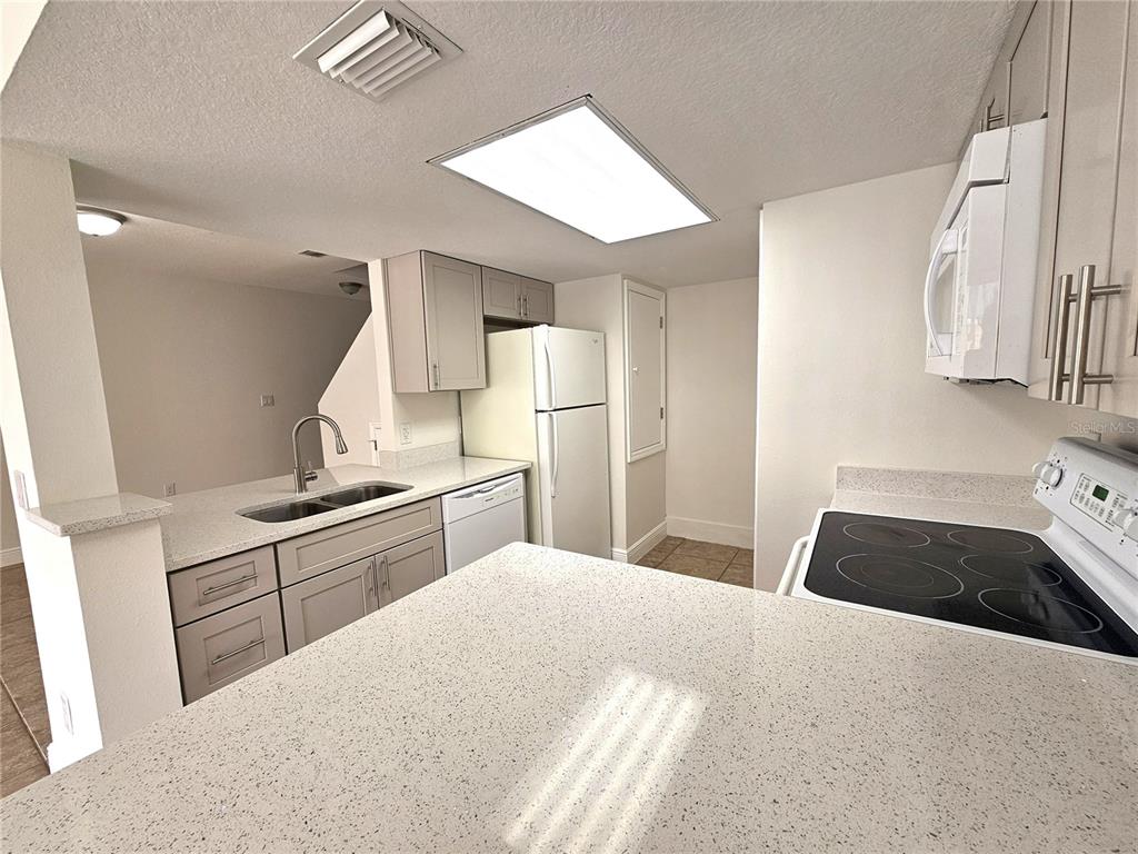 411 Australian Way Davenport, FL 33897 - Photo 7 of 24 a kitchen with granite countertop a sink stove and refrigerator