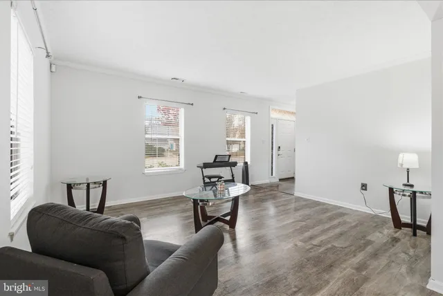 a living room with couches chandelier and a dining table with wooden floor