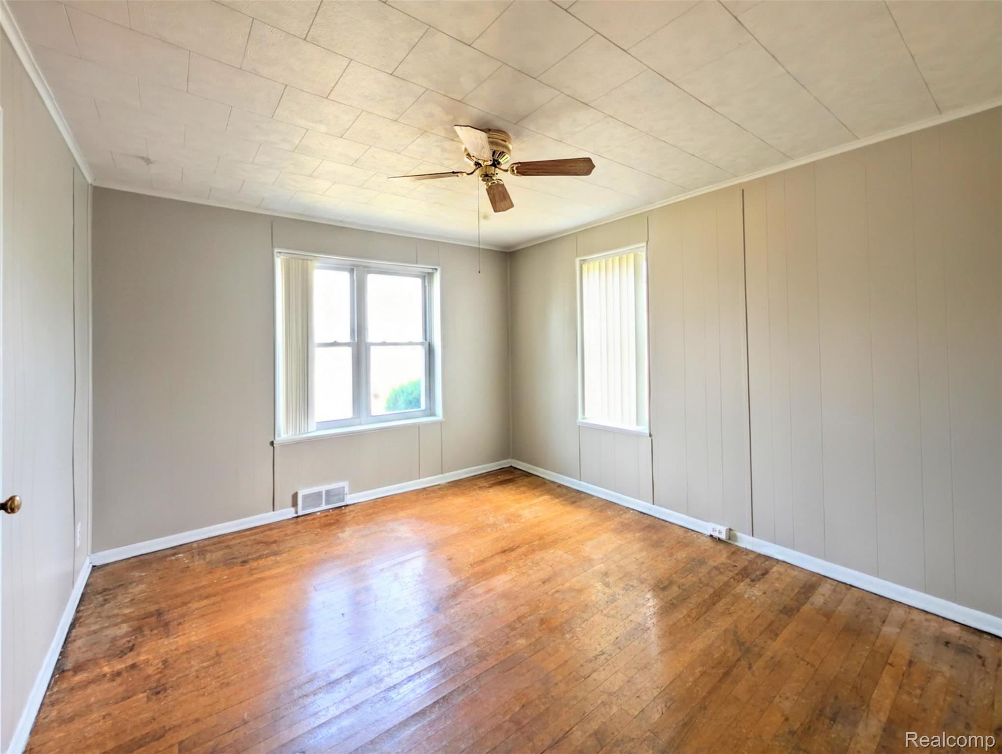 2173 West Mount Morris Road Mount Morris, MI 48458 - Photo 7 of 18 Bright, light-filled bedroom showcasing gleaming wood-finish flooring, neutral wall finishes, and abundant natural light from dual windows