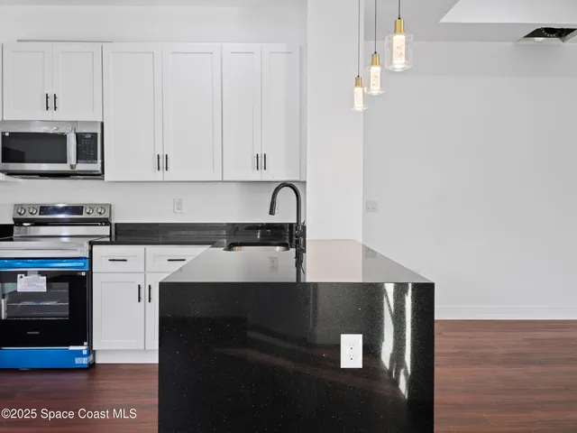 a kitchen with stainless steel appliances granite countertop a sink a stove a refrigerator a center island and cabinets