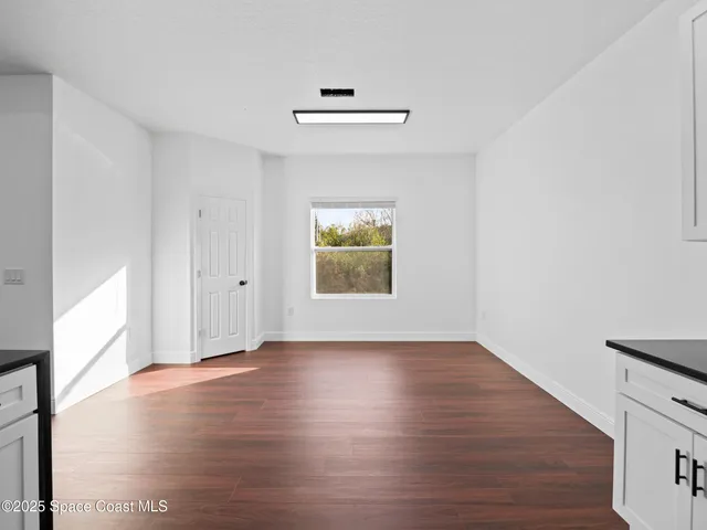 a kitchen with stainless steel appliances white cabinets a sink and wooden floor