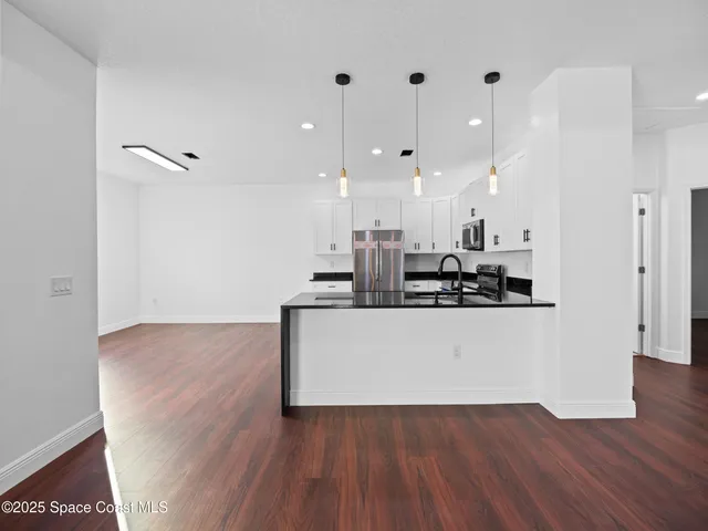 a view of an empty room with wooden floor and a ceiling fan