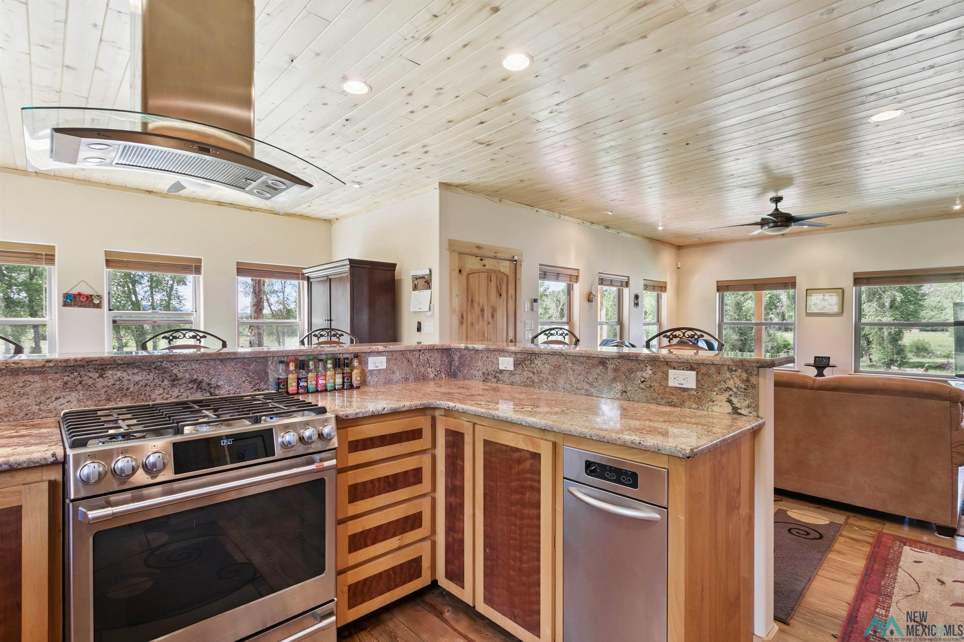 31 Cr 343 Road Chama, NM 87520 - Photo 44 of 44 Kitchen featuring stainless steel gas range, light stone counters, open floor plan, island range hood, and wood ceiling