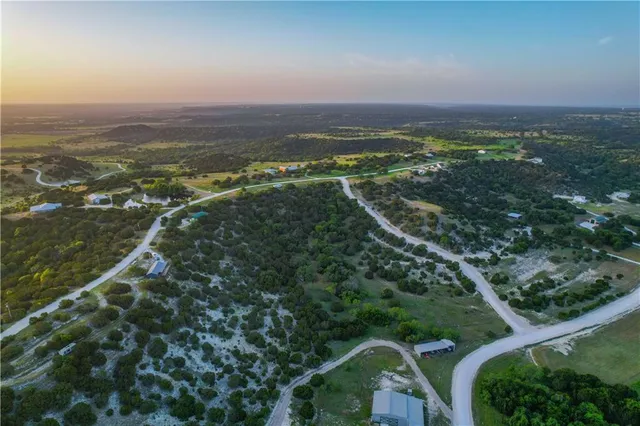 an aerial view of residential houses with outdoor space and trees
