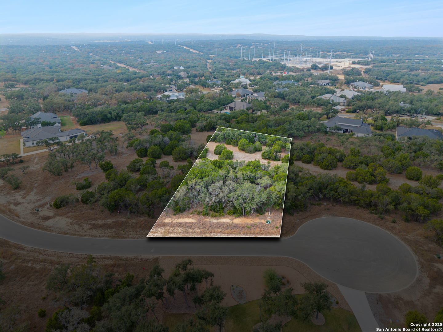 an aerial view of a residential houses with outdoor space and trees