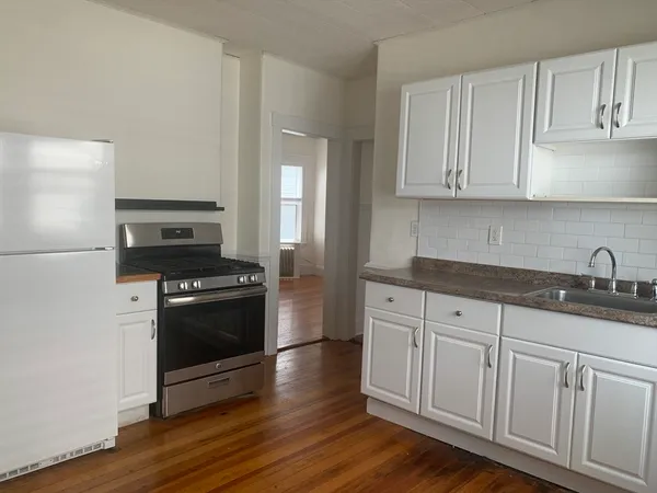 a kitchen with granite countertop white cabinets and stainless steel appliances
