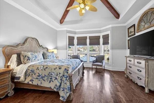 a bedroom with a large bed and a flat tv screen on dresser