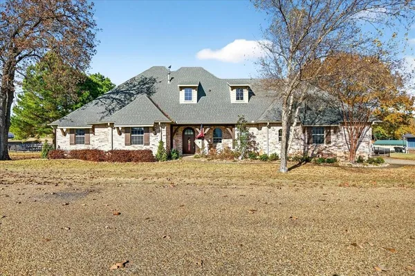 a front view of a house with a dirt yard and a large tree