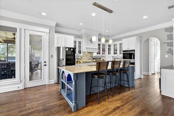 an open kitchen with kitchen island wooden floor center island and stainless steel appliances