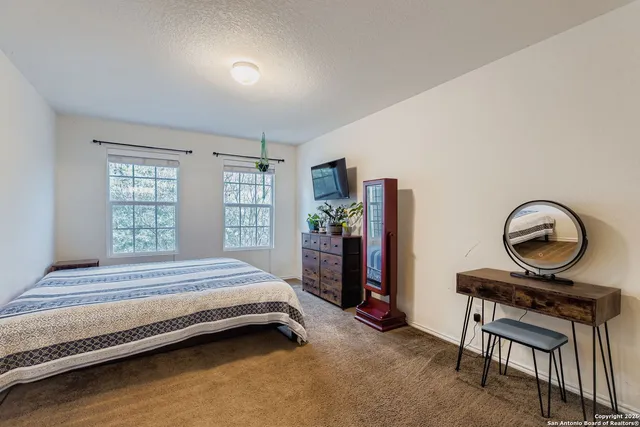 a spacious bedroom with a bed a dresser and a large window
