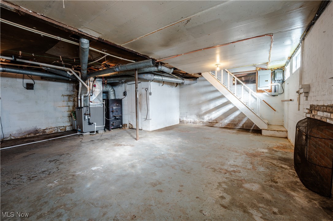4829 Frys Valley Road Southwest Port Washington, OH 43837 - Photo 21 of 46 Unfinished basement featuring electric panel, heating unit, water heater, and stairs