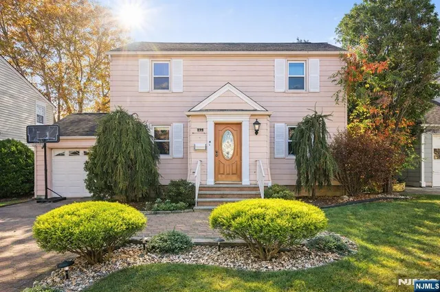 a view of a white house with a small yard and large tree
