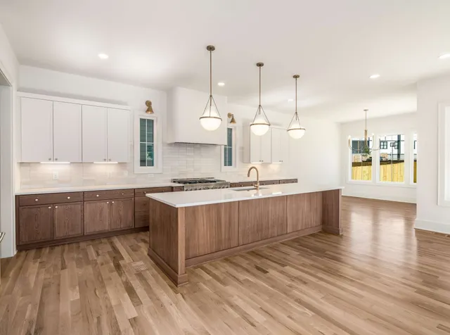 a large kitchen with stainless steel appliances kitchen island granite countertop a large stove a sink dishwasher and a wooden cabinets