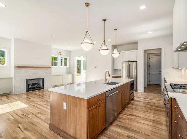 a open kitchen with stainless steel appliances granite countertop a sink a counter space a stove and a wooden floors
