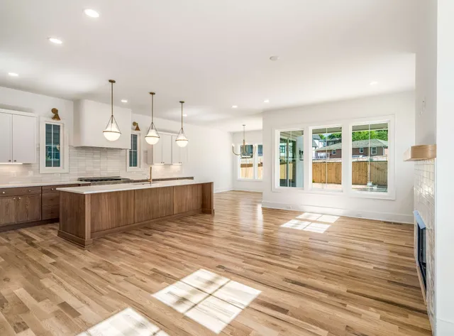 a large white kitchen with kitchen island a sink wooden floor and a counter top space