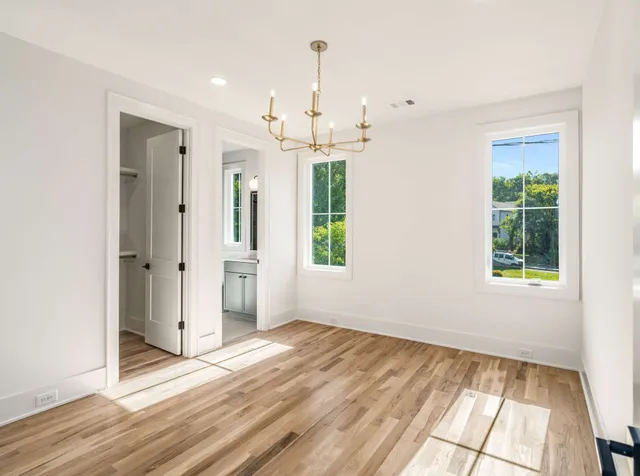 an empty room with wooden floor cabinet and windows