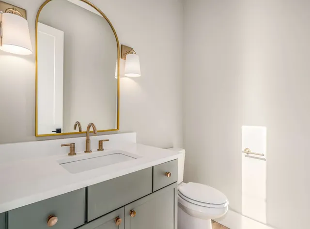 a bathroom with a sink toilet vanity and mirror