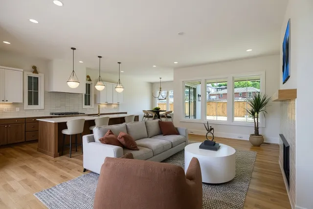 a living room with furniture kitchen view and a large window